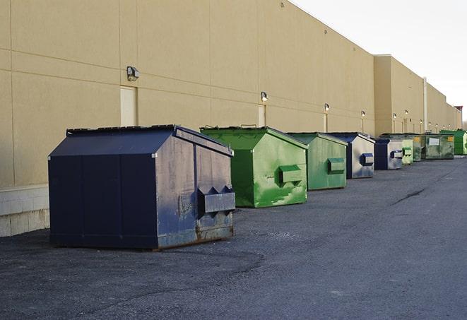 a waste management truck unloading into a construction dumpster in Bethpage, NY